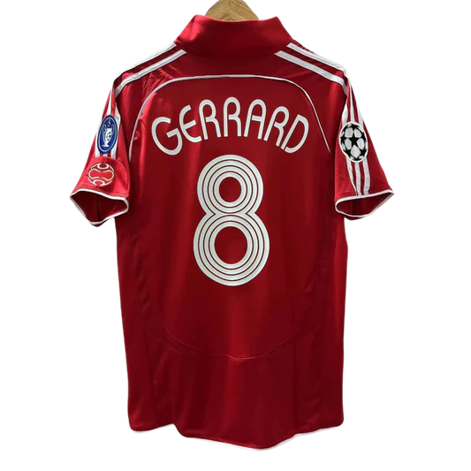 Originálny Liverpool FC dres z legendárnej sezóny 2004/2005, kedy klub vyhral Ligu majstrov. Červená farba s bielymi detailmi, meno "GERRARD" a číslo 8 – ikonický kapitán Steven Gerrard. Na rukávoch sú nášivky Ligy majstrov vrátane finálovej sezóny a počtu titulov.